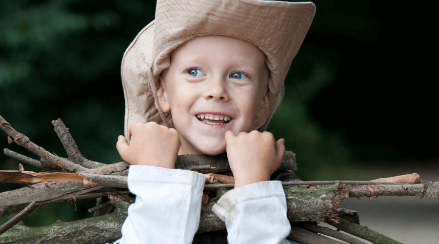 Junge mit Ästen Kind im Wald